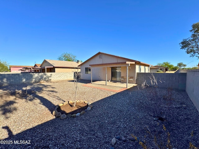rear view of property featuring a fenced backyard, a patio area, and stucco siding