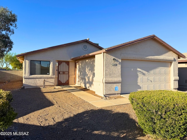 ranch-style house featuring an attached garage, fence, and stucco siding