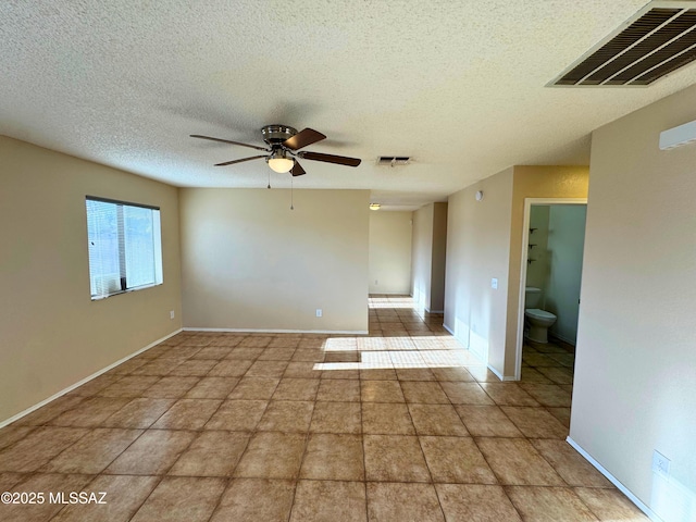 tiled spare room featuring visible vents, a ceiling fan, and a textured ceiling