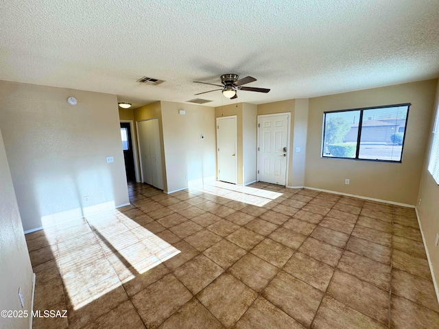 empty room with baseboards, ceiling fan, a textured ceiling, and visible vents