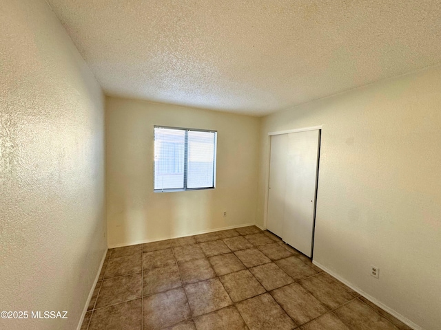 unfurnished bedroom with baseboards, a closet, tile patterned floors, and a textured ceiling