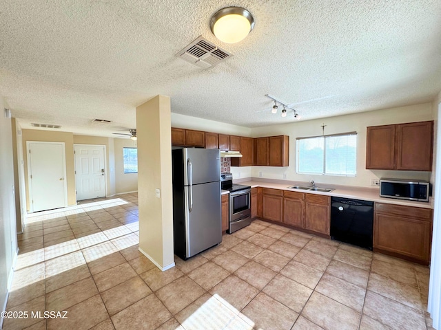 kitchen with a textured ceiling, visible vents, rail lighting, a sink, and stainless steel appliances