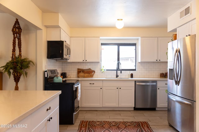 7302 E Placita Sinaloa, Tucson, AZ 85710 - kitchen with stainless steel appliances, a sink, tasteful backsplash, light countertops, and white cabinetry