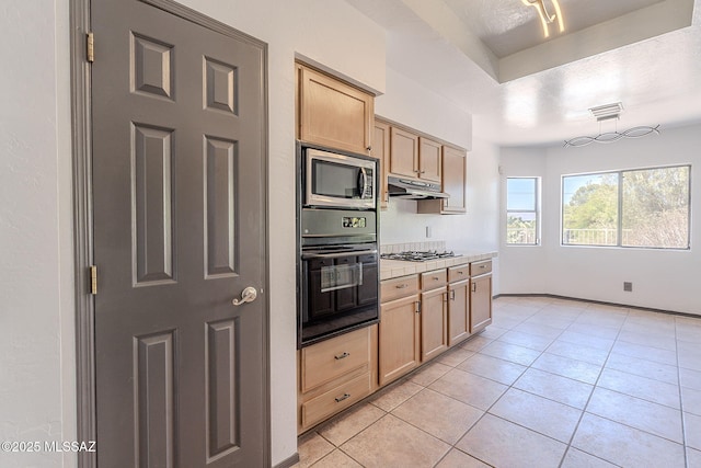kitchen featuring stainless steel microwave, oven, gas cooktop, under cabinet range hood, and light brown cabinets