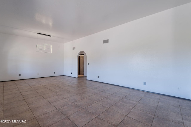 spare room with tile patterned flooring, arched walkways, baseboards, and visible vents