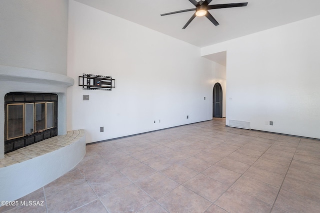 unfurnished living room with baseboards, visible vents, ceiling fan, tile patterned floors, and arched walkways