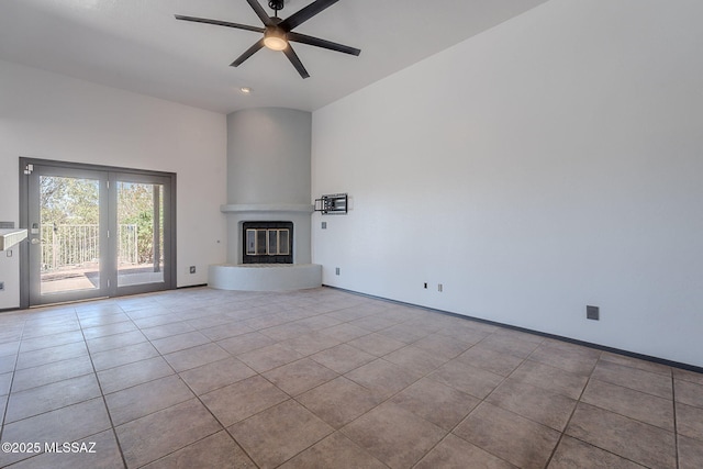 unfurnished living room featuring a ceiling fan, tile patterned flooring, a glass covered fireplace, and baseboards