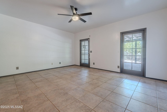 spare room featuring a ceiling fan, baseboards, and light tile patterned floors