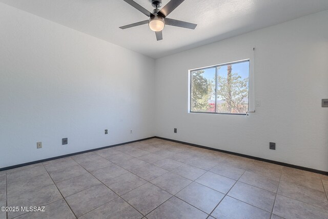 tiled spare room featuring baseboards and a ceiling fan