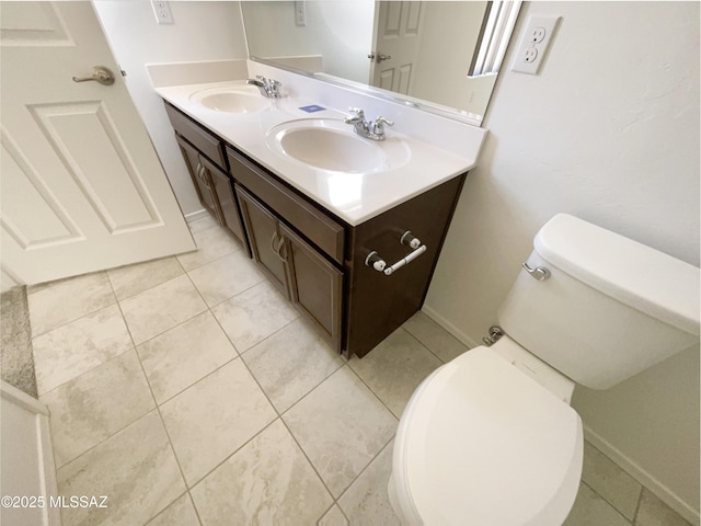 bathroom with a sink, tile patterned flooring, toilet, and double vanity