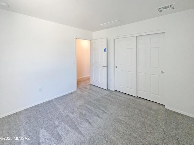 unfurnished bedroom featuring carpet floors, baseboards, a closet, and visible vents