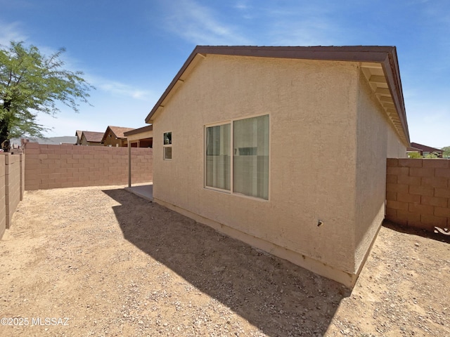 view of side of property with a fenced backyard and stucco siding