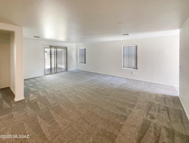 unfurnished room with carpet flooring, baseboards, and visible vents