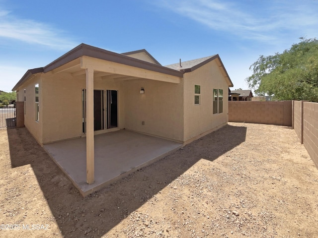 rear view of house with a fenced backyard, stucco siding, and a patio area