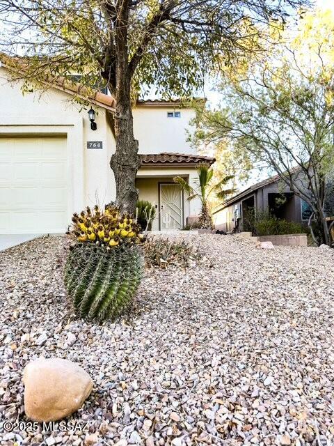 view of front of house with a garage, stucco siding, and a tiled roof