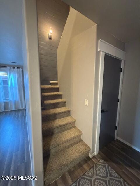 staircase featuring baseboards and wood finished floors
