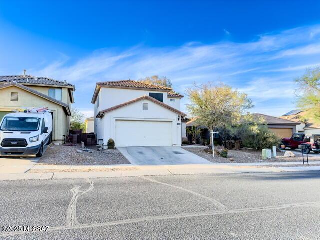 mediterranean / spanish home with a tiled roof, stucco siding, driveway, and a garage