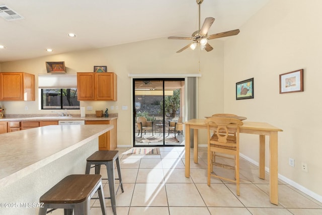 kitchen with a healthy amount of sunlight, visible vents, vaulted ceiling, light countertops, and a breakfast bar