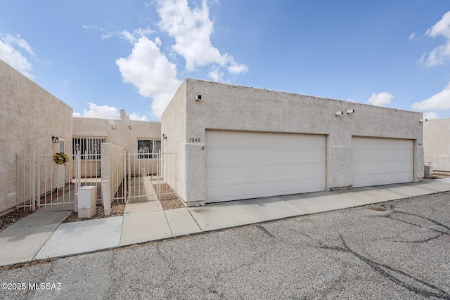 7848 E 35th St, Tucson, AZ 85710 - view of front of property with stucco siding, a garage, and a gate