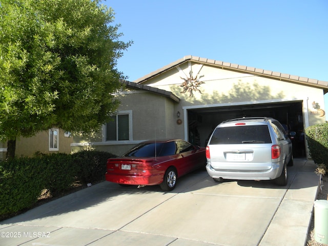 view of front facade with a garage, driveway, and stucco siding