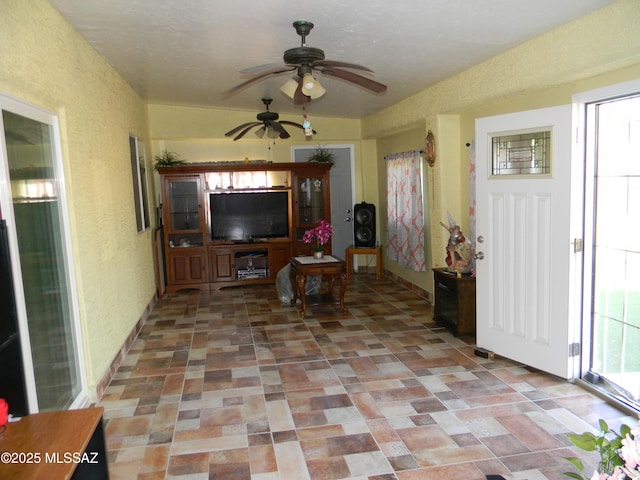 living area with a textured wall and a ceiling fan