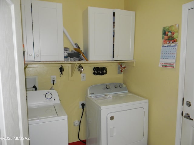 clothes washing area featuring cabinet space and washer and clothes dryer