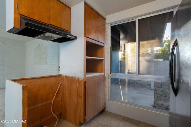 8133 E 6th St, Tucson, AZ 85710 - kitchen with under cabinet range hood, light tile patterned floors, brown cabinetry, and freestanding refrigerator