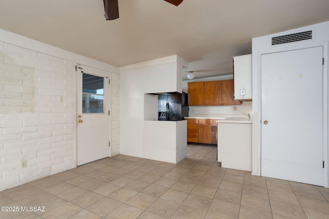 8133 E 6th St, Tucson, AZ 85710 - kitchen with black fridge, ceiling fan, light countertops, brown cabinets, and a sink