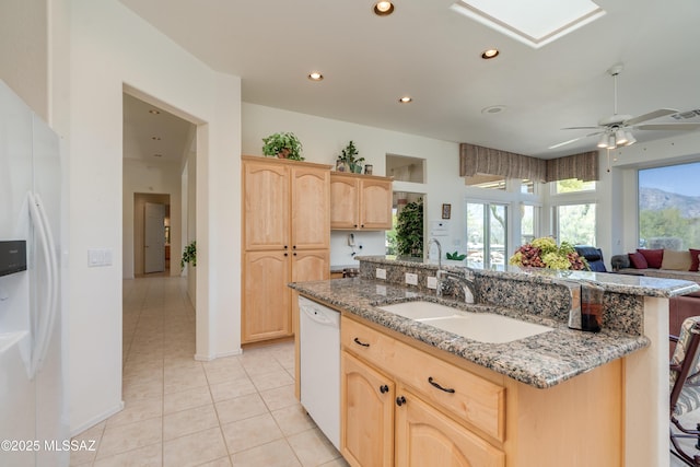 kitchen featuring a sink, light brown cabinetry, white appliances, and open floor plan