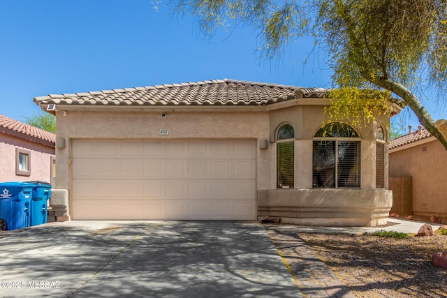 mediterranean / spanish home with concrete driveway, a tiled roof, an attached garage, and stucco siding