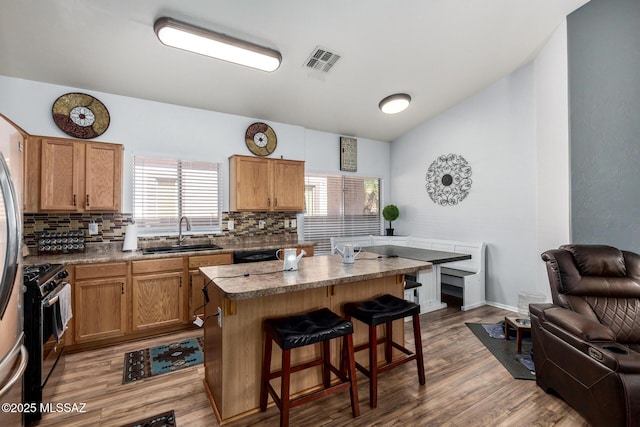 kitchen with a sink, tasteful backsplash, stainless steel range with gas cooktop, and visible vents