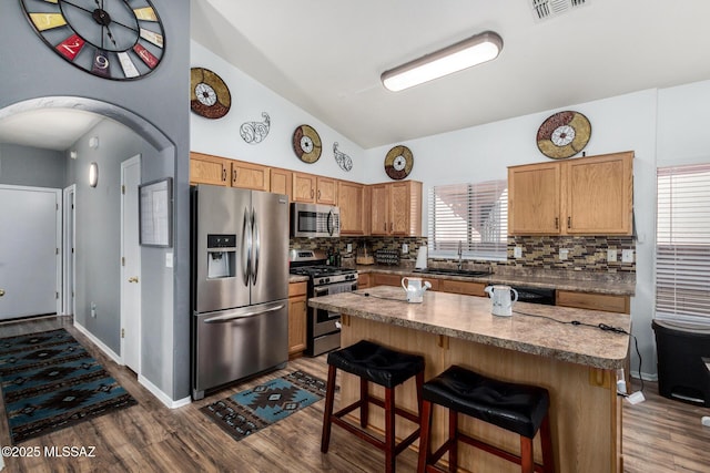 kitchen featuring dark wood-style flooring, appliances with stainless steel finishes, tasteful backsplash, a sink, and lofted ceiling