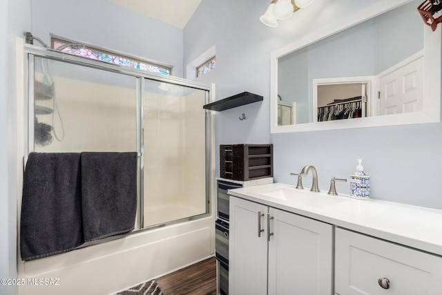full bathroom with shower / bath combination with glass door, a walk in closet, wood finished floors, and vanity
