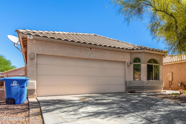 mediterranean / spanish home featuring a tiled roof, a garage, stucco siding, and driveway