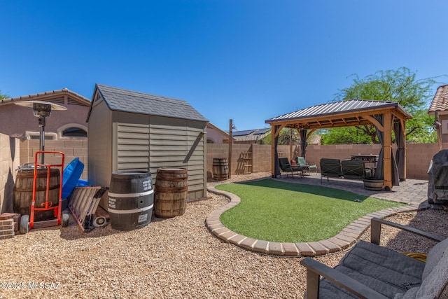 view of yard with a gazebo, a storage shed, a fenced backyard, an outbuilding, and a patio
