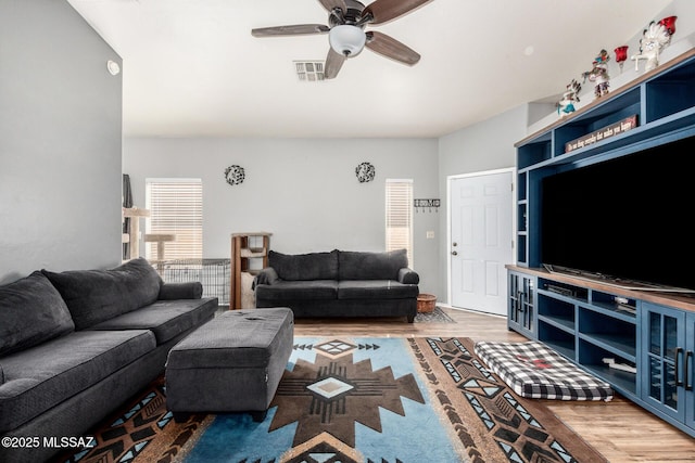 living room with a ceiling fan, visible vents, and wood finished floors