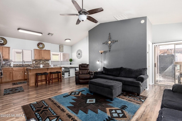 living area featuring ceiling fan, visible vents, wood finished floors, and lofted ceiling