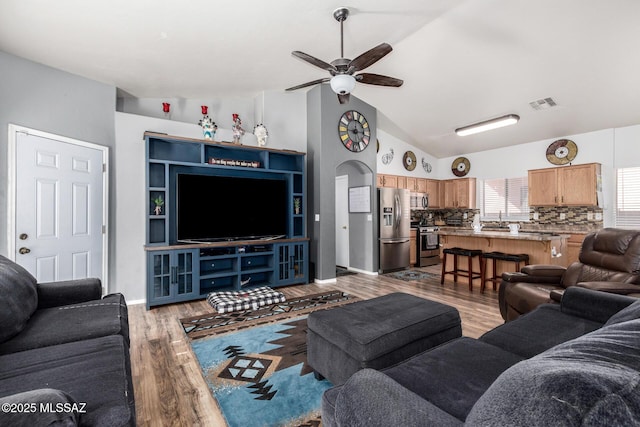 living room with a ceiling fan, lofted ceiling, wood finished floors, and visible vents
