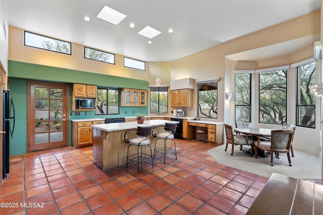 12431 E Cape Horn Dr, Tucson, AZ 85749 - kitchen featuring black appliances, light countertops, a breakfast bar, a kitchen island, and a towering ceiling