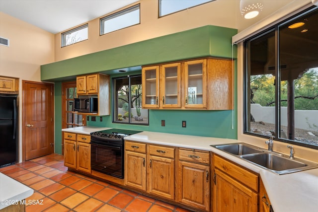 12431 E Cape Horn Dr, Tucson, AZ 85749 - kitchen featuring black appliances, a sink, a towering ceiling, light countertops, and brown cabinets