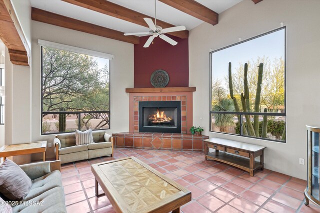 12431 E Cape Horn Dr, Tucson, AZ 85749 - tiled living area featuring beam ceiling, a warm lit fireplace, and a ceiling fan
