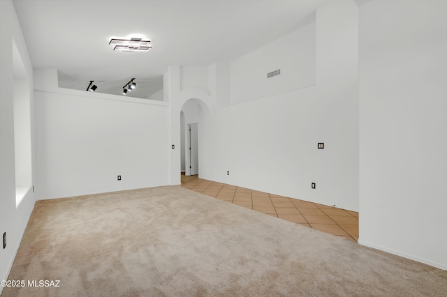 114 W Freddie Canyon Way, Oro Valley, AZ 85755 - tiled empty room with carpet flooring, a high ceiling, track lighting, arched walkways, and visible vents
