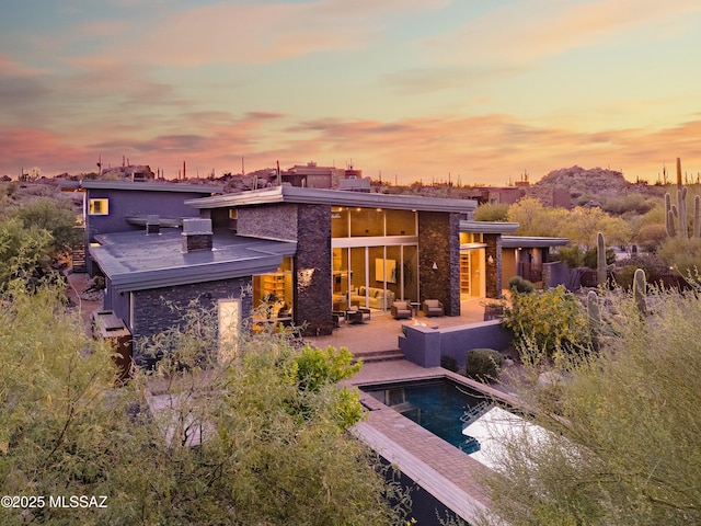 back of house at dusk with a patio area