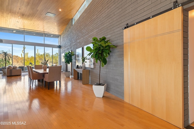 dining area with wood finished floors, recessed lighting, floor to ceiling windows, and a high ceiling