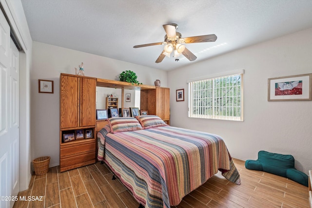bedroom featuring a closet, wood tiled floor, baseboards, and ceiling fan