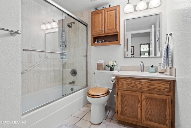 full bath featuring a textured wall, tile patterned flooring, vanity, toilet, and enclosed tub / shower combo