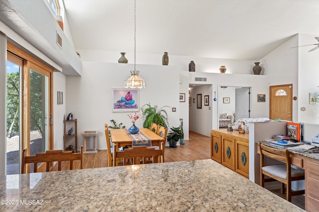 dining space with vaulted ceiling, a ceiling fan, light wood-style flooring, and visible vents