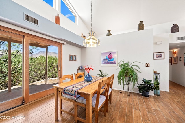 dining room with light wood-style floors, plenty of natural light, visible vents, and a notable chandelier