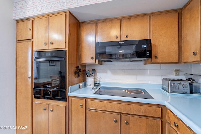 kitchen featuring light countertops, brown cabinets, and black appliances
