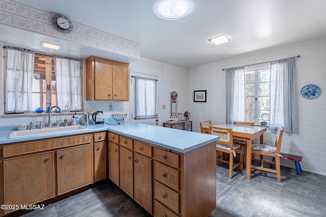 kitchen featuring a sink, light countertops, brown cabinetry, and a peninsula